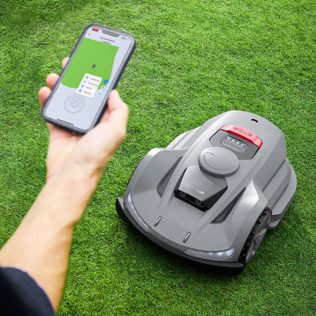 Using app to guide remote-controlled lawn mower cutting grass in a yard