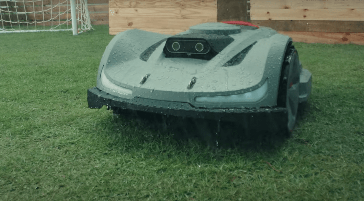 Robotic lawn mower paused on wet grass during rain, demonstrating its built-in rain detection feature